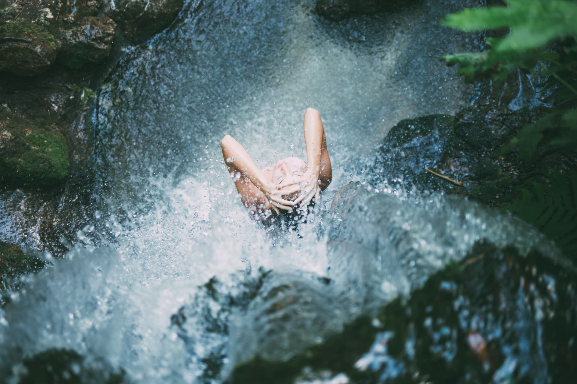 Person enjoying a refreshing natural waterfall massage, symbolizing the calming power of hydro massage and bodywork.